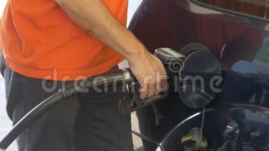 有人给汽车加油。 男人`用汽油泵给他的车加满油。